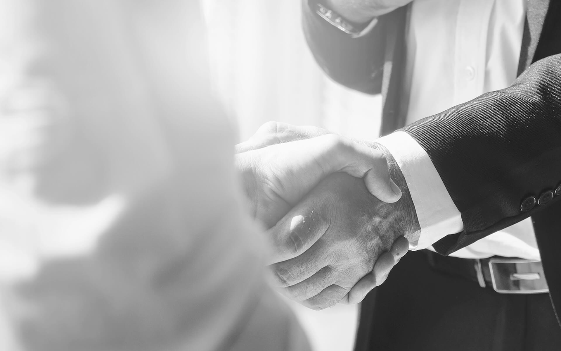 Verbindlicher Handschlag zwischen zwei Geschäftspartnern, der eine erfolgreiche Zusammenarbeit und gegenseitiges Vertrauen symbolisiert.